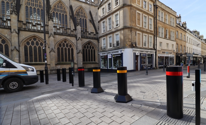 Black bollards with red and yellow bands on a paved street